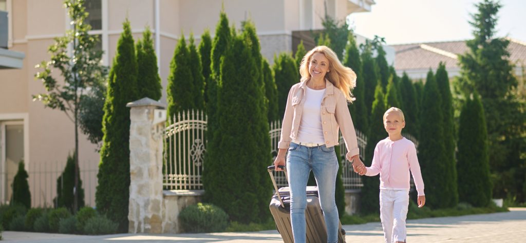 woman carrying a suitcase and holding her doughter's hand