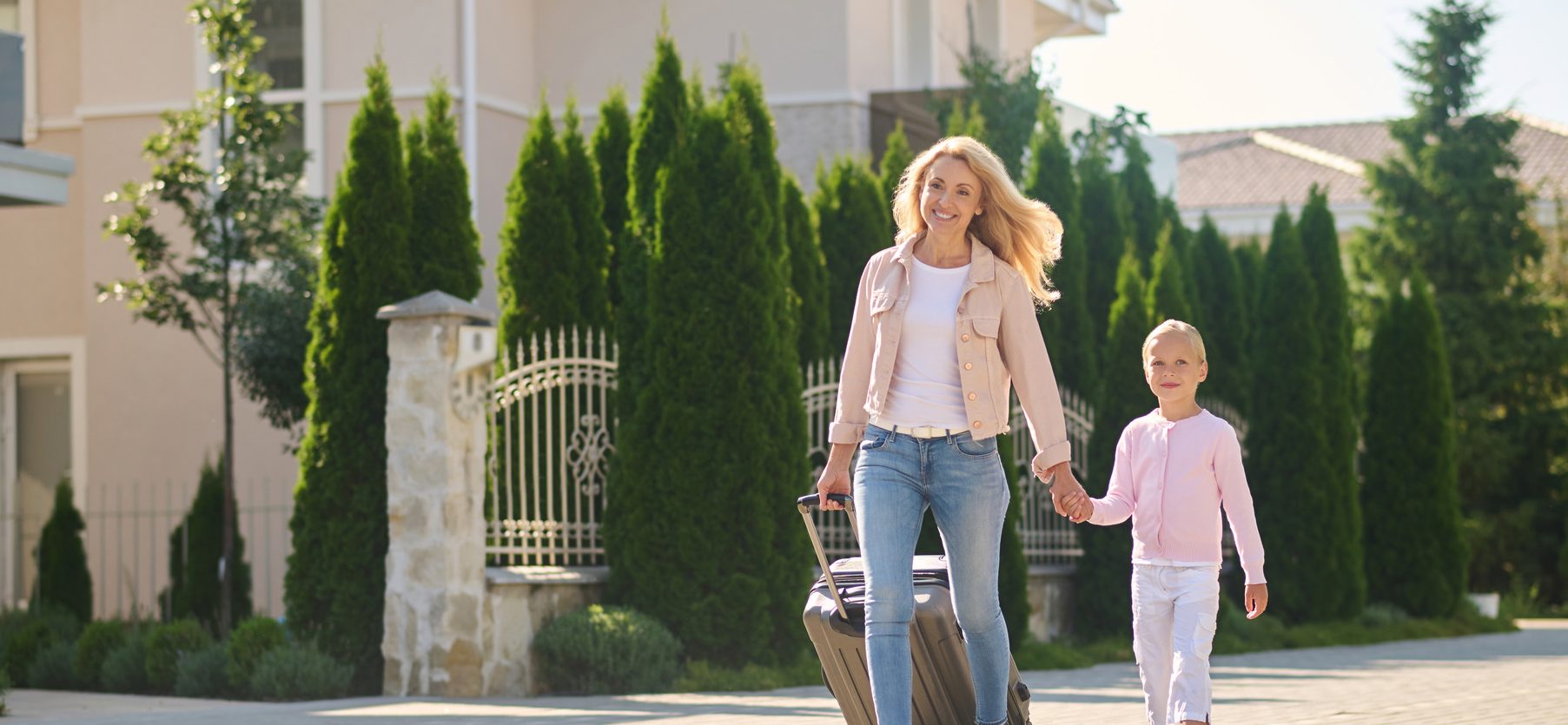 woman carrying a suitcase and holding her doughter's hand