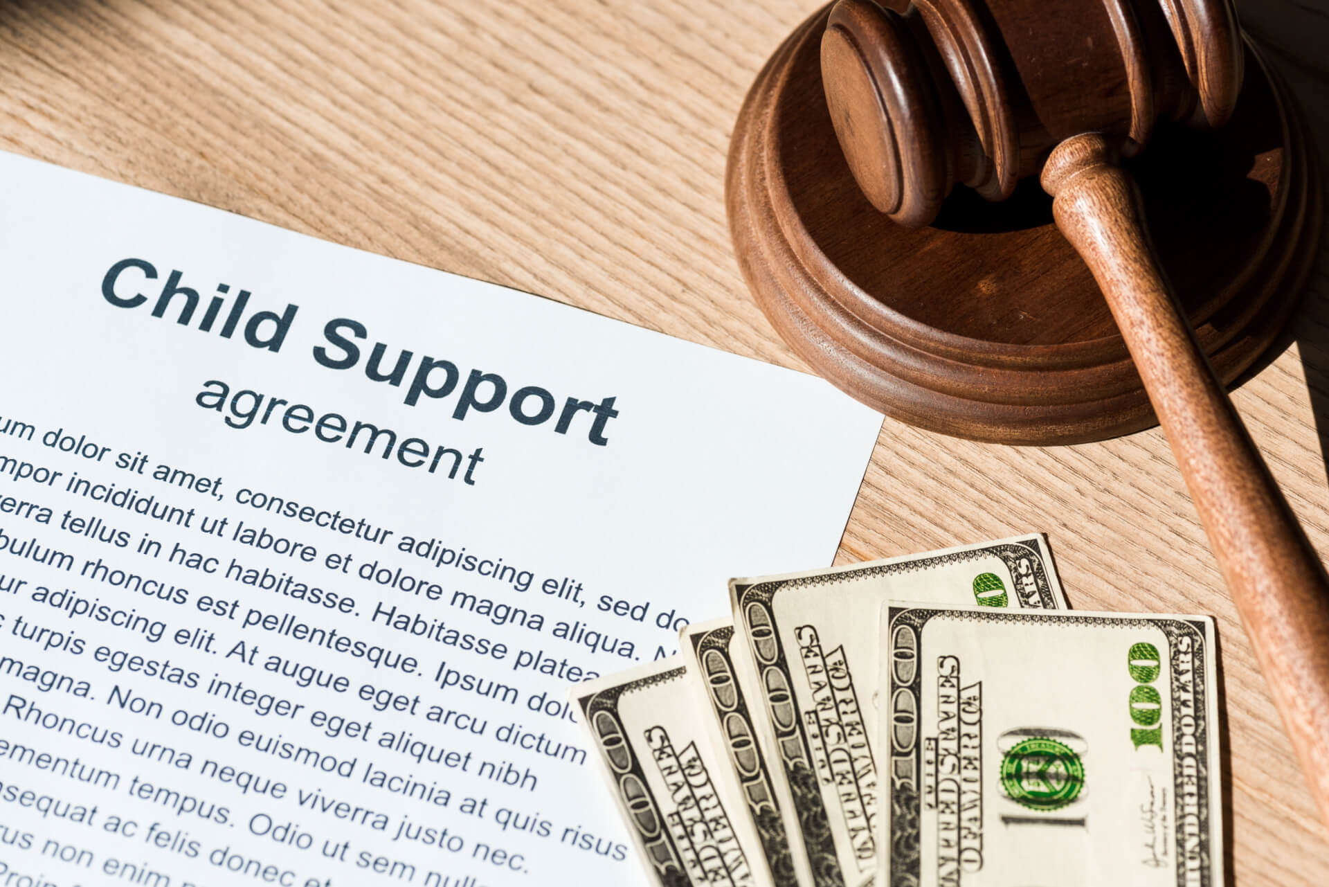 A child support agreement sits on a wooden table alongside a judge’s gavel and cash, symbolizing legal and financial responsibilities handled by a divorce attorney in Laguna Beach.