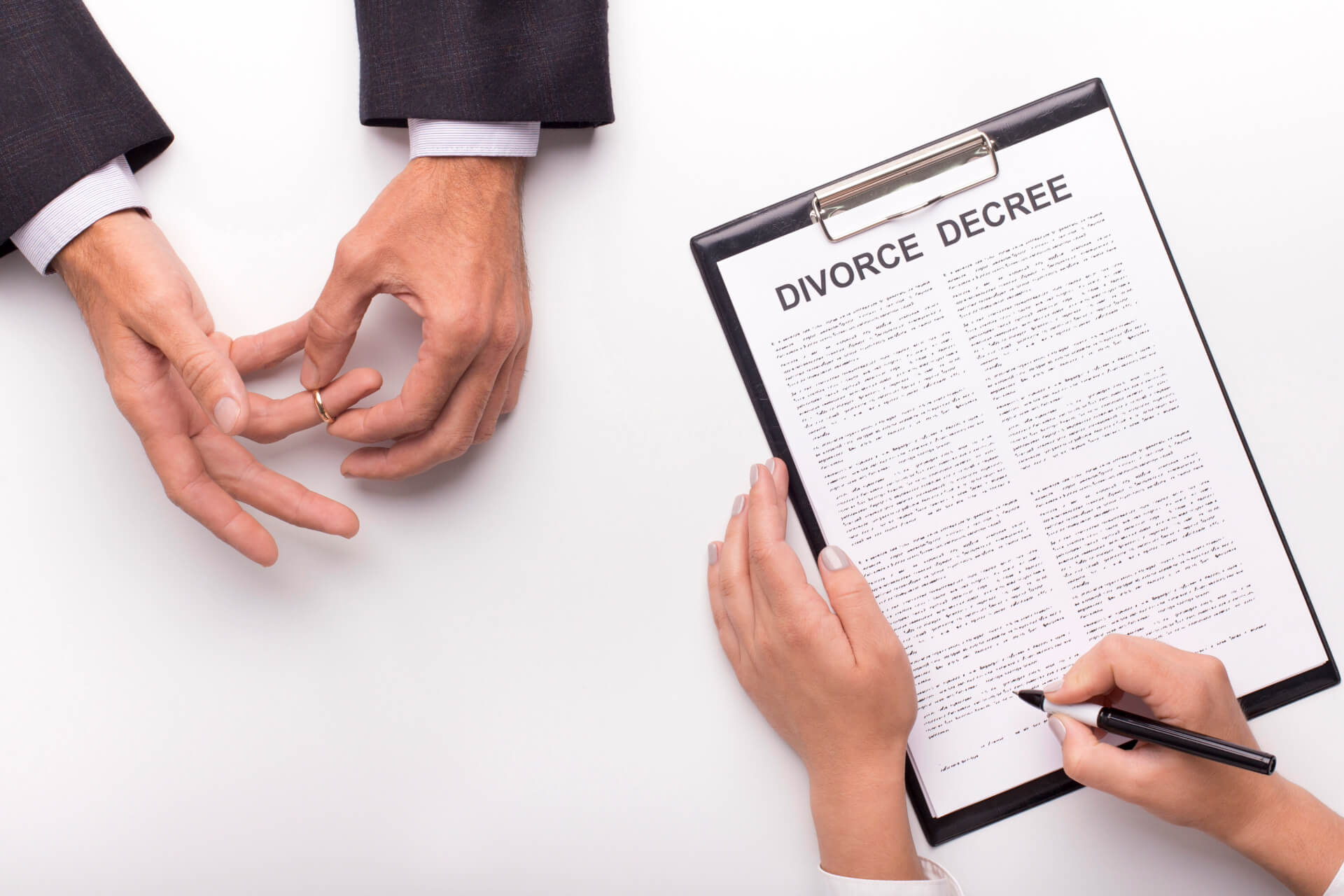 A person removes their wedding ring while another signs a divorce decree, symbolizing the legal end of a marriage and the importance of a divorce lawyer in San Clemente.