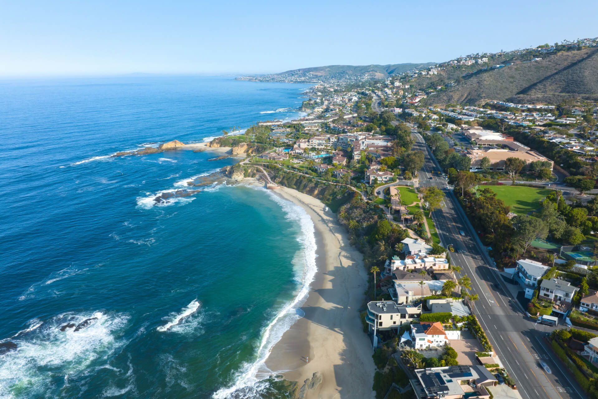 A breathtaking aerial view of Laguna Beach, California, featuring the coastline, ocean waves, and hillside homes, representing the region served by a Laguna Beach divorce attorney.