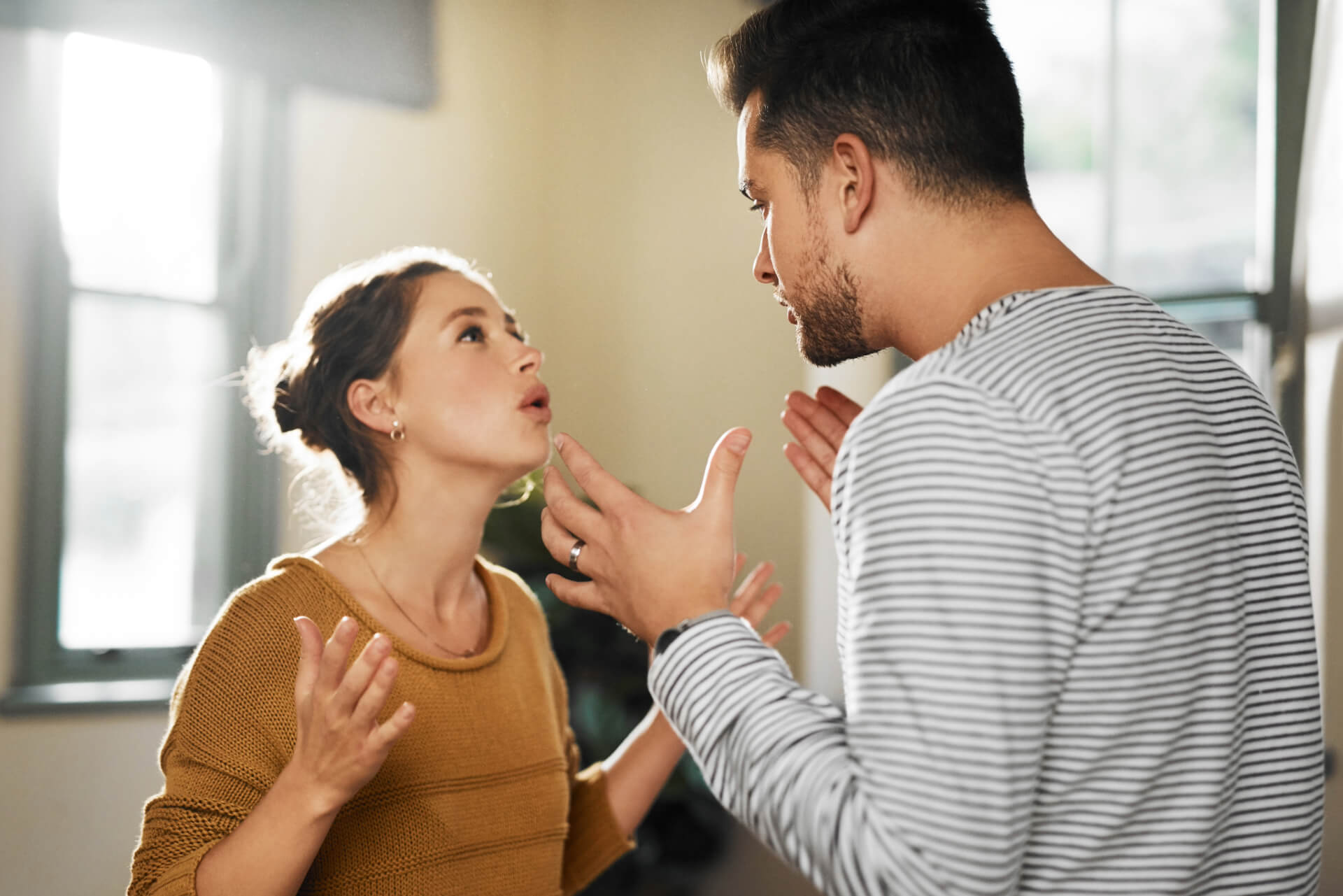 A couple argues intensely in a sunlit room, reflecting marital conflict and the need for legal guidance from a Newport Beach divorce attorney.