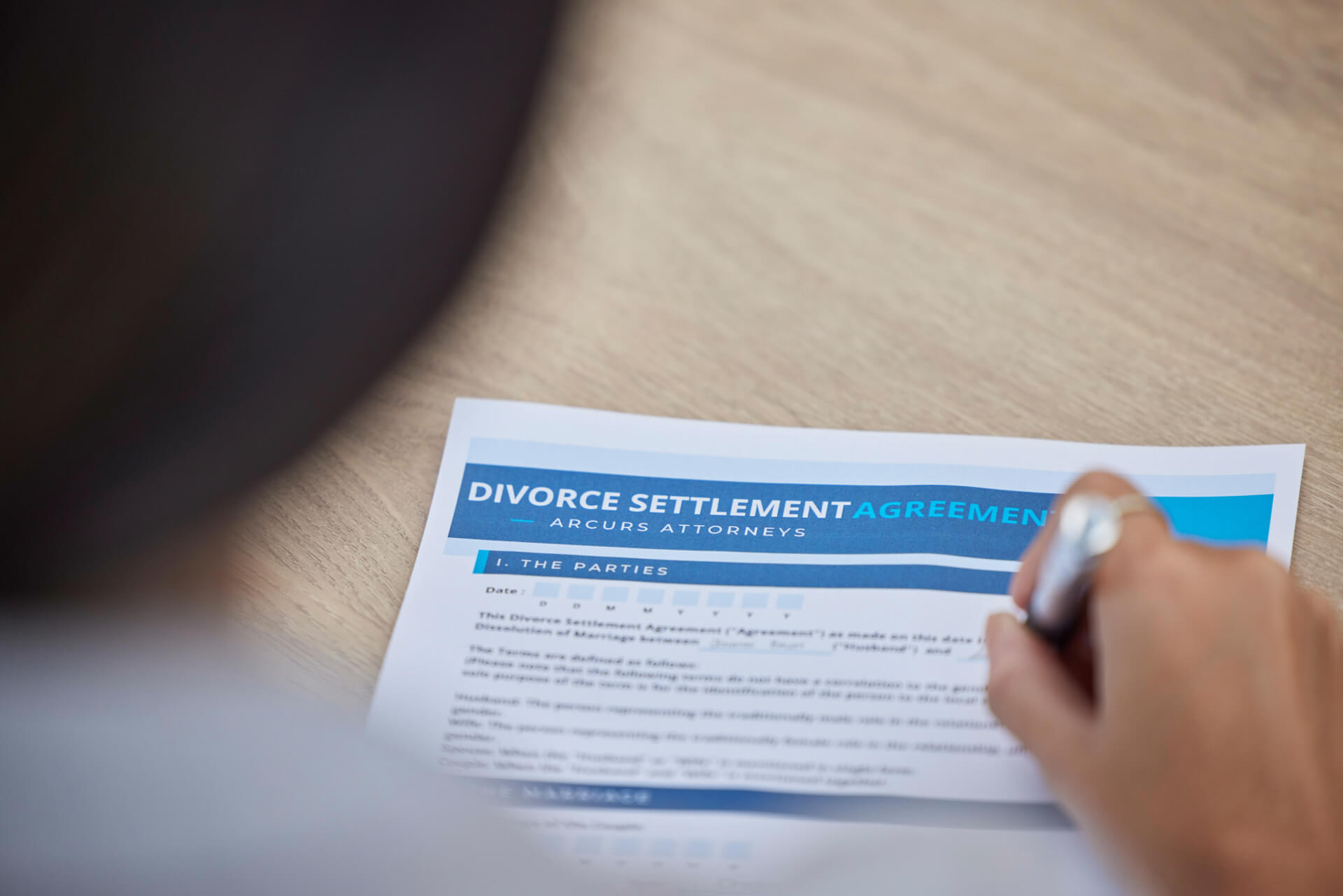 A person signs a divorce settlement agreement, representing the legal process of separation and the importance of having a San Diego divorce lawyer for guidance.