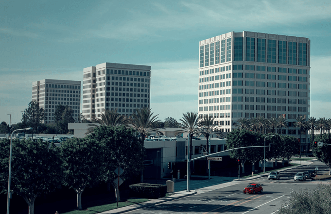 Irvine, California, cityscape with modern office buildings, palm trees, and a busy intersection.
